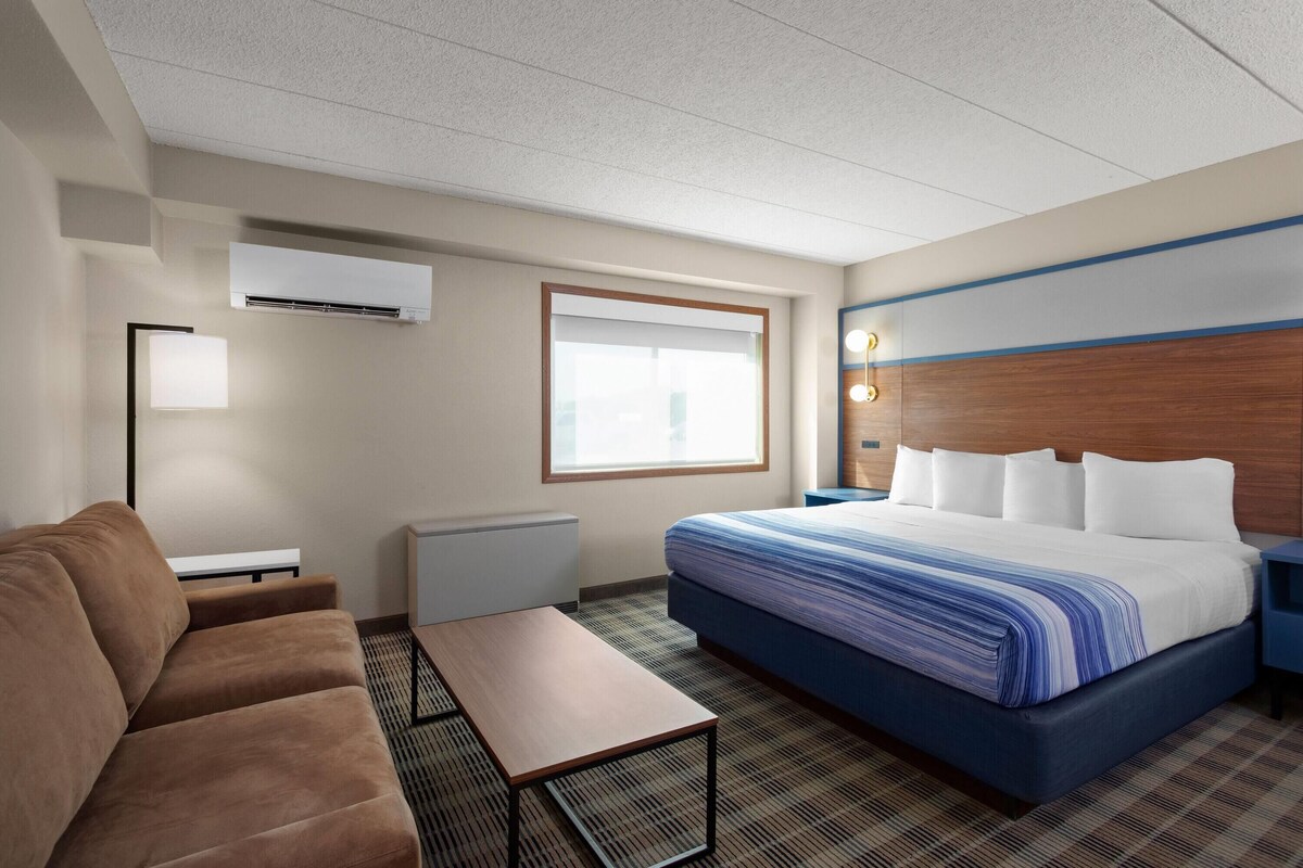 A hotel room with a bed, a sofa, a table, and a window.