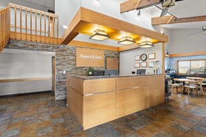 A reception area with a wooden counter, a sign reading "AmericInn by Wyndham," and a staircase leading to an upper level. - AmericInn by Wyndham Roseau (Roseau)