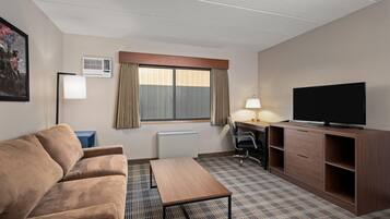 Een hotelkamer met een bank, een bureau, een televisie, een lamp en een radiator.