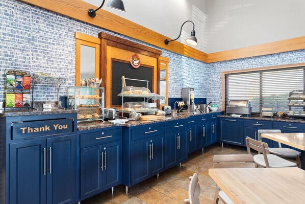 A kitchen with blue cabinets, a "Thank You" sign, a coffee station, and a window with blinds. - AmericInn by Wyndham Roseau (Roseau)