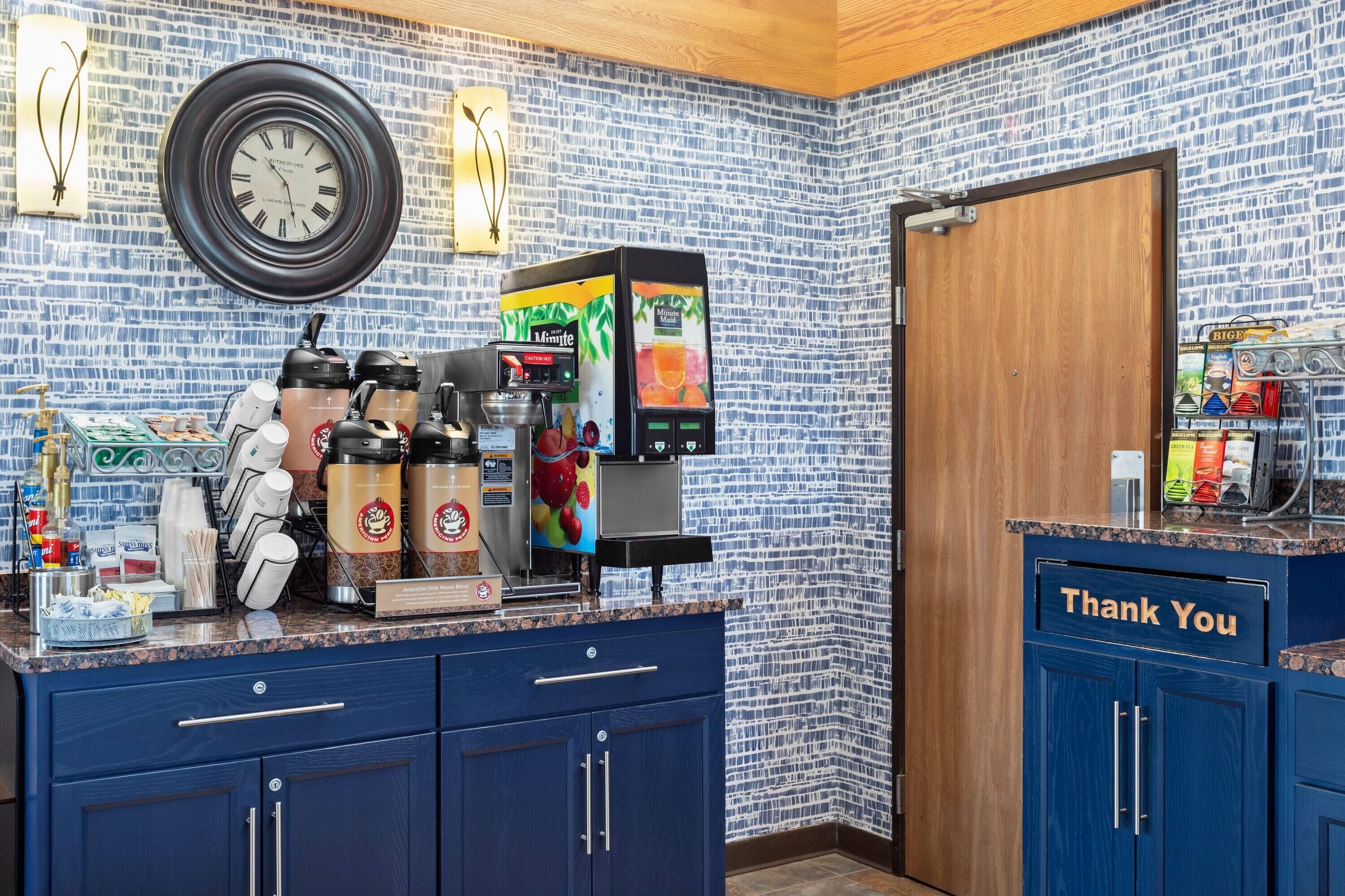 Une cuisine équipée d’une machine à café, d’une horloge et d’une pancarte « Merci » posée sur le comptoir.