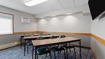 A conference room with tables and chairs, a projector screen, and a window.