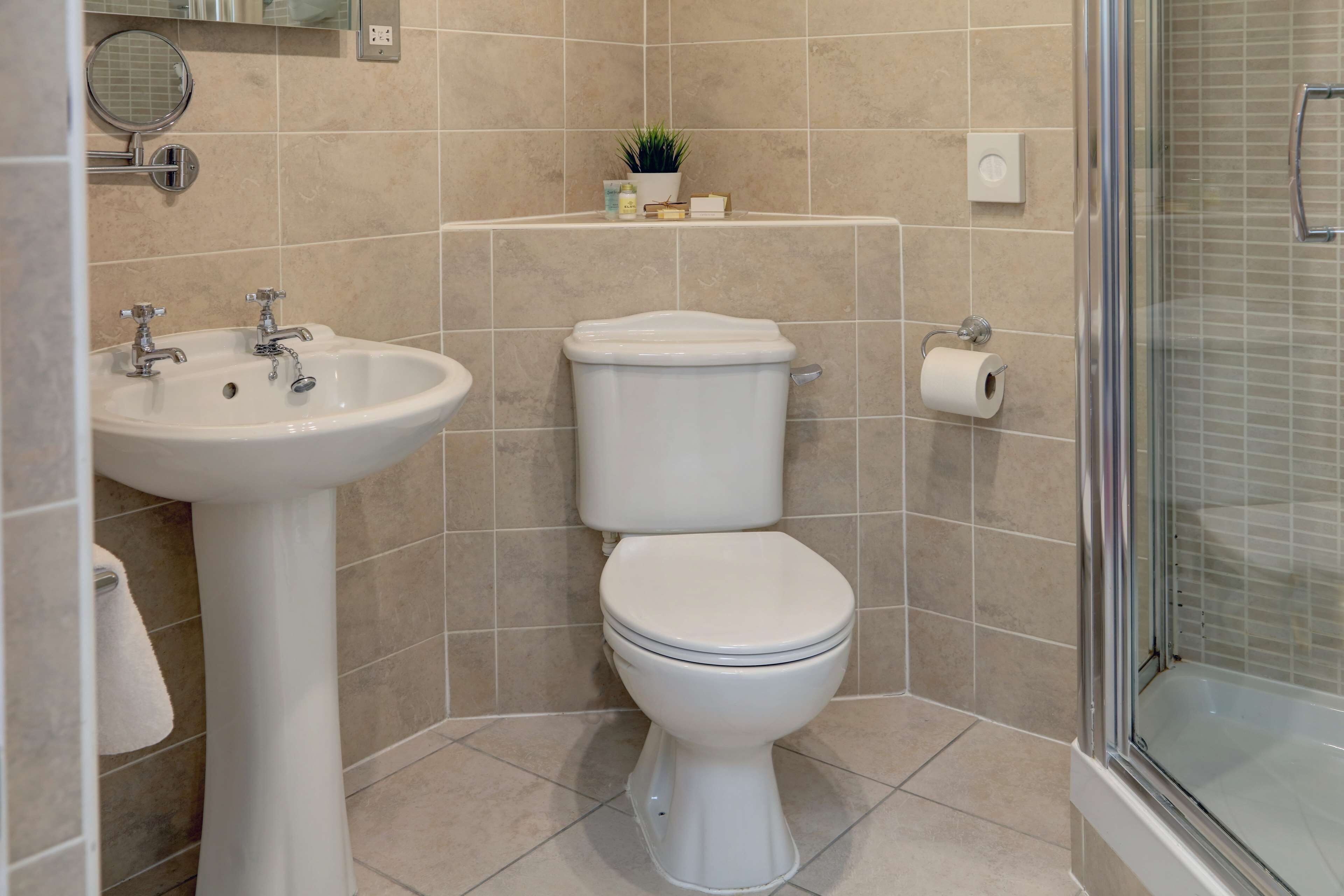 Un baño con lavamanos pedestal, inodoro y cabina de ducha de vidrio.