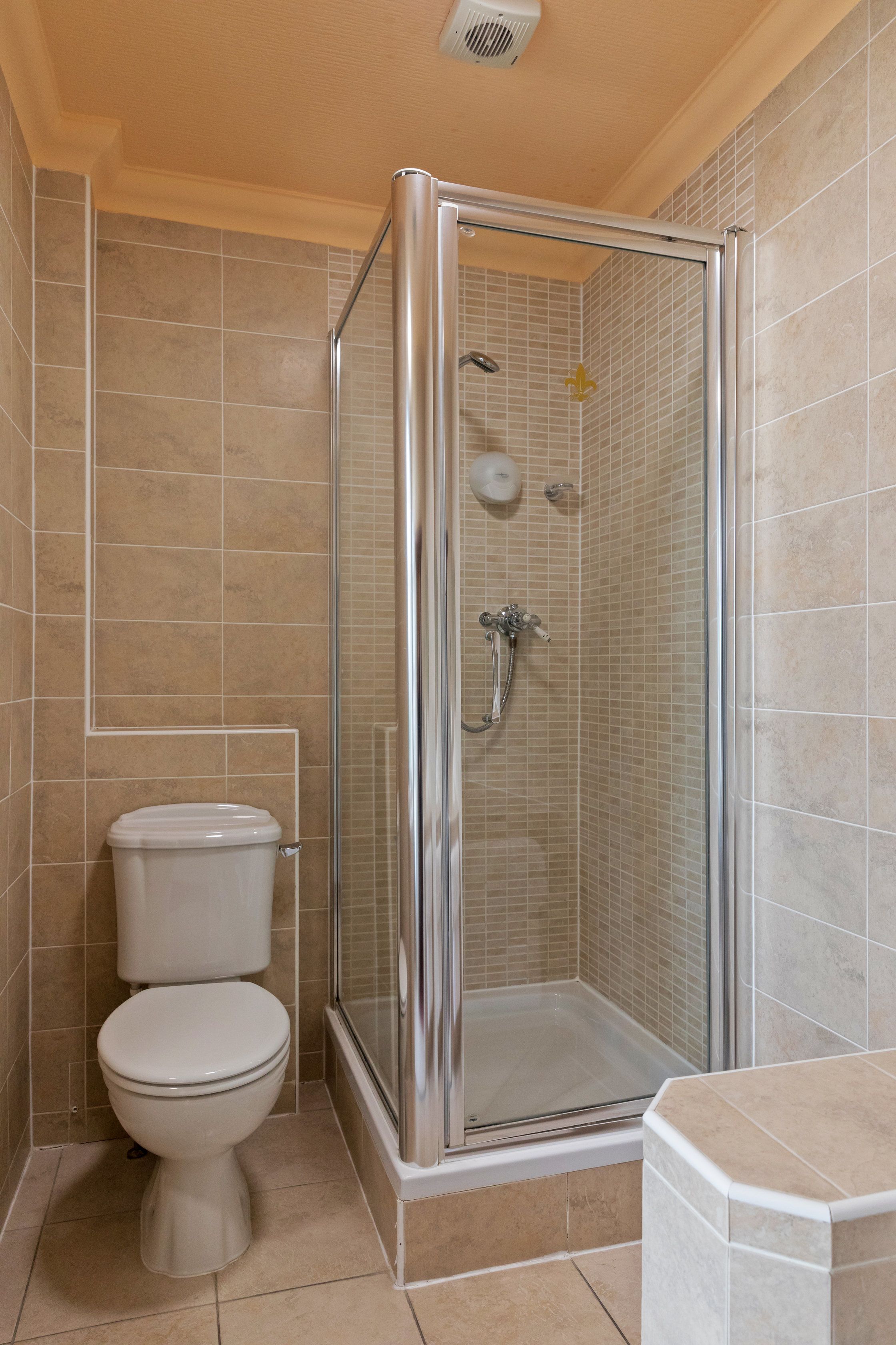 Un baño con ducha de vidrio, inodoro y lavamanos.