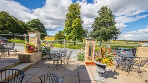 An outdoor patio with stone pillars, metal chairs, and tables.