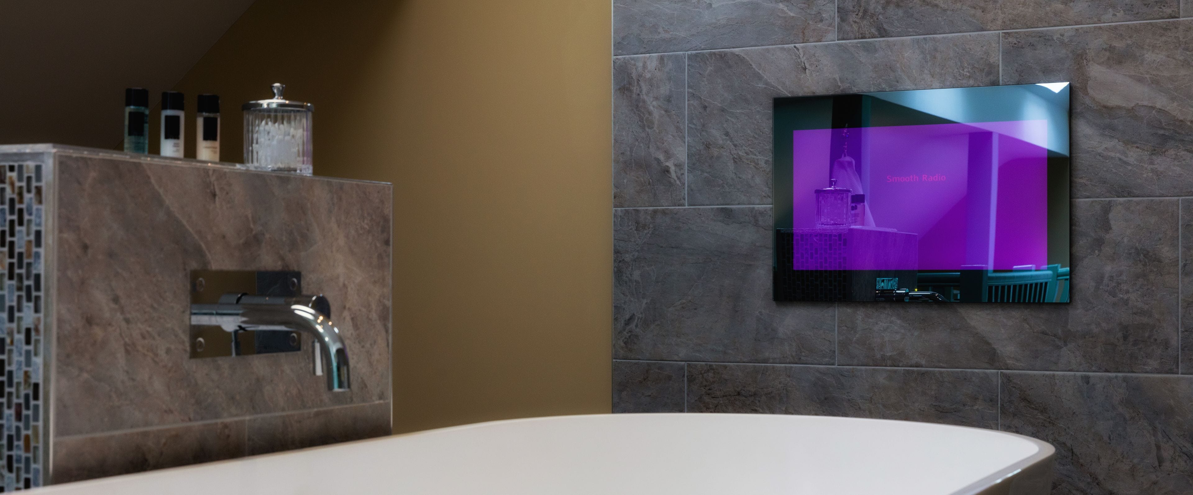 Un baño moderno con pared de mármol, radio incorporada y una bañera blanca.