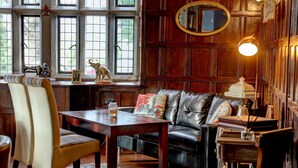 A cozy living room with a leather sofa, a wooden coffee table, and a fireplace.