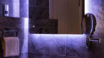 A bathroom with a sink, mirror, towel rack, and toilet paper dispenser.