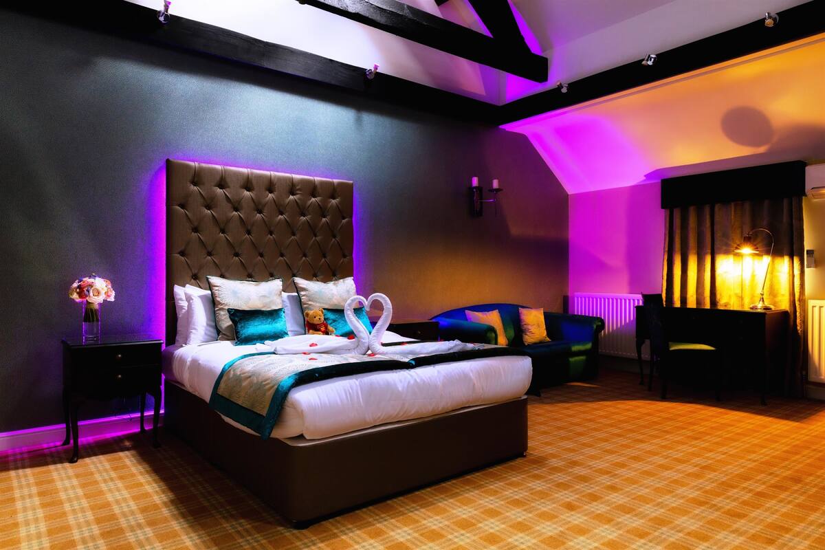 A modern hotel room with a large bed, a nightstand, a chair, and a desk.