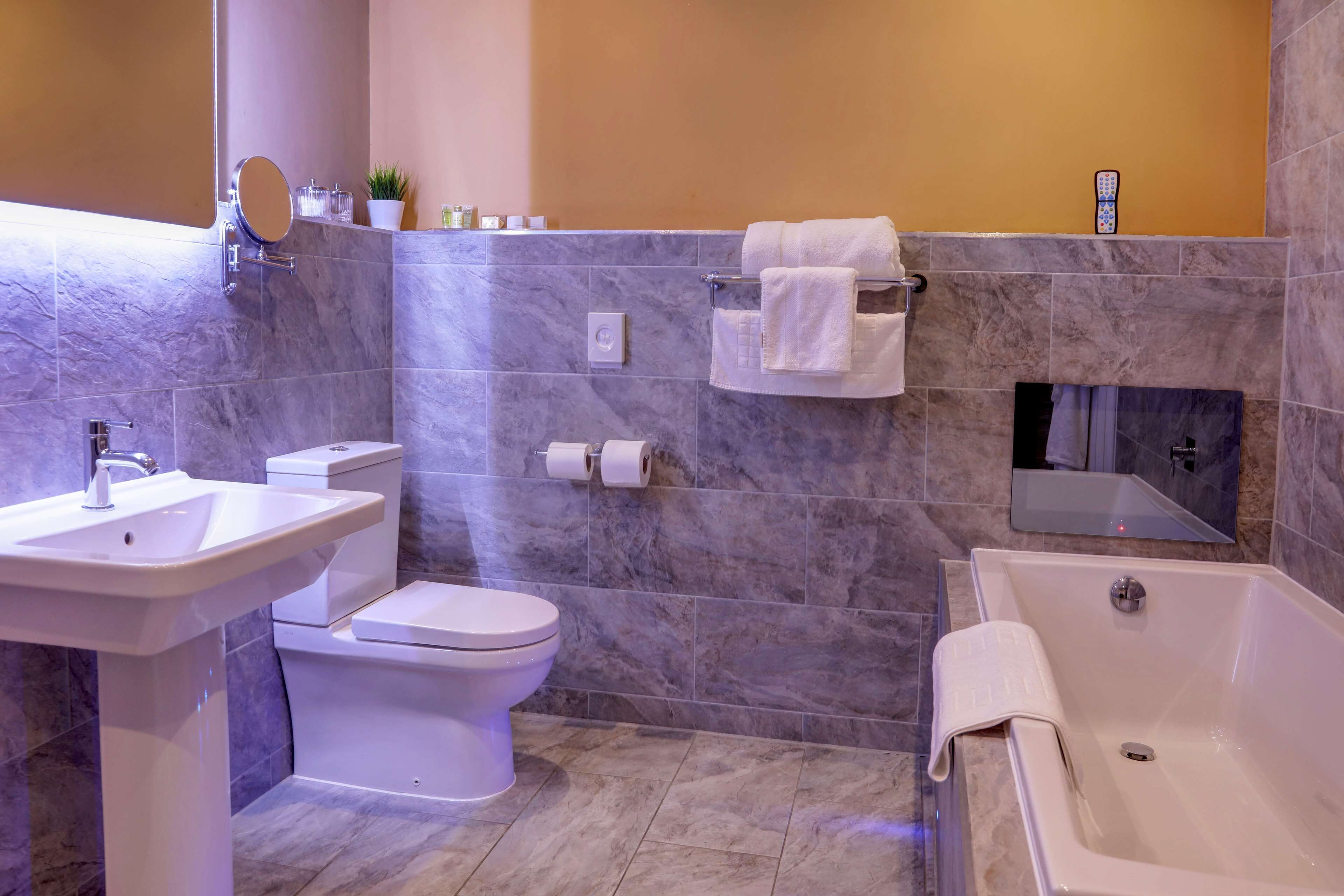 A modern bathroom with a sink, toilet, and bathtub.