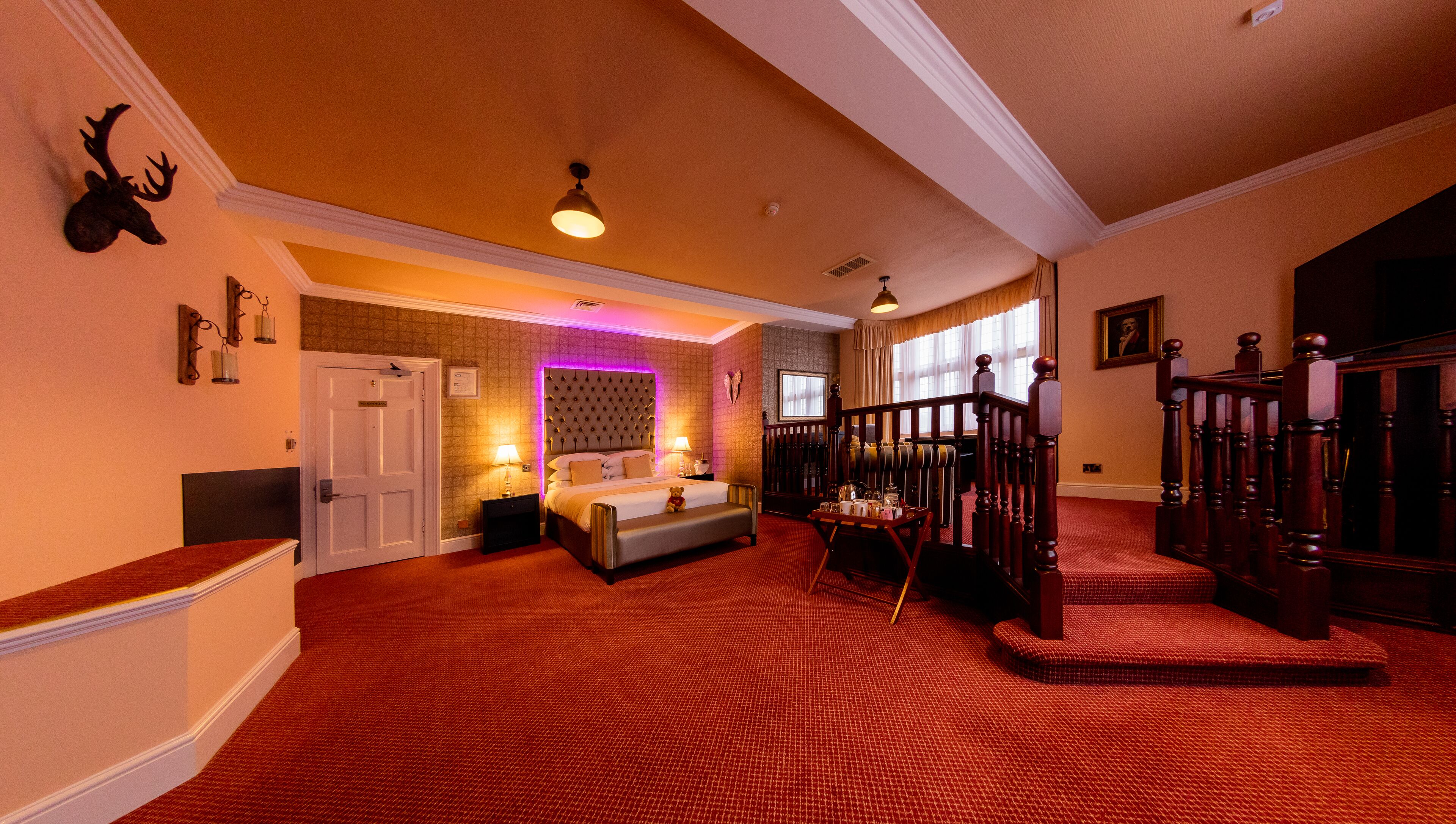 A spacious hotel room with a large bed, a sitting area, and a staircase leading to another level.