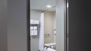 A narrow bathroom with a shower curtain, a towel rack with folded towels, and a small bench. - Hyatt Place Mt Laurel (Mount Laurel)