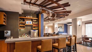 A modern bar area with a long counter, bar stools, and shelves stocked with bottles. - Hyatt Place Mt Laurel (Mount Laurel)