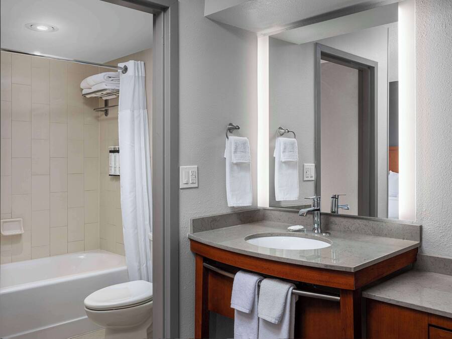 A modern bathroom with a bathtub, toilet, and vanity with a sink and mirror.