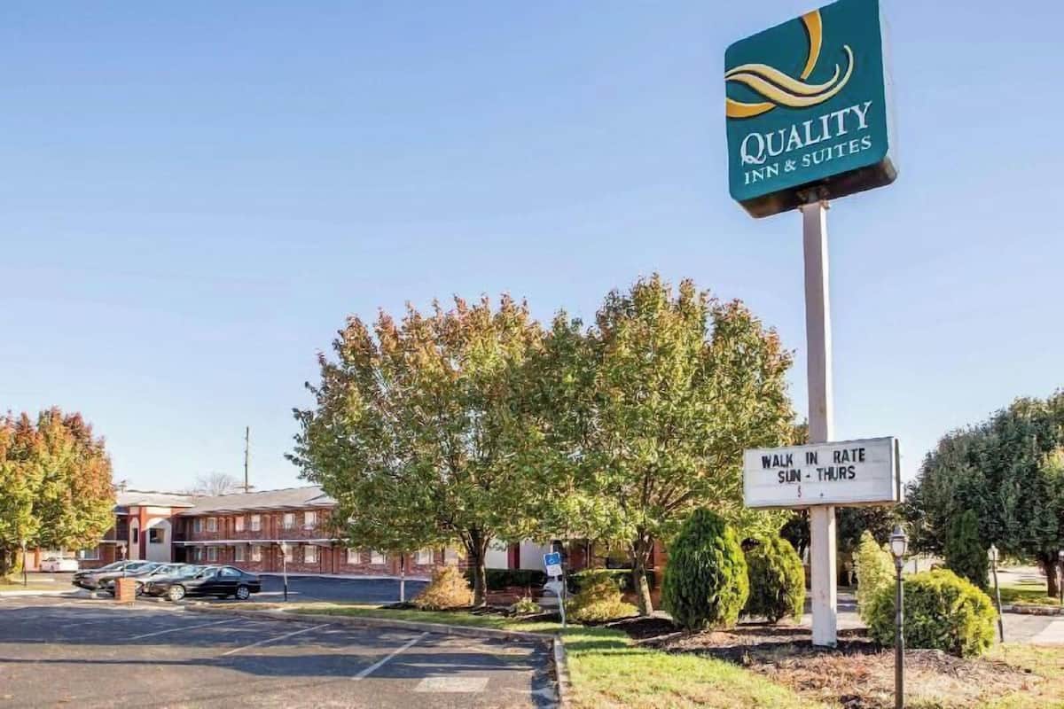 Señal de Quality Inn & Suites, un estacionamiento y un letrero que indica 'Tarifa por Entrada'.