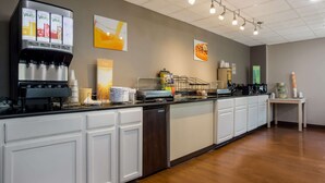 A modern kitchen area with a coffee machine, a dishwasher, and a small table with condiments.
