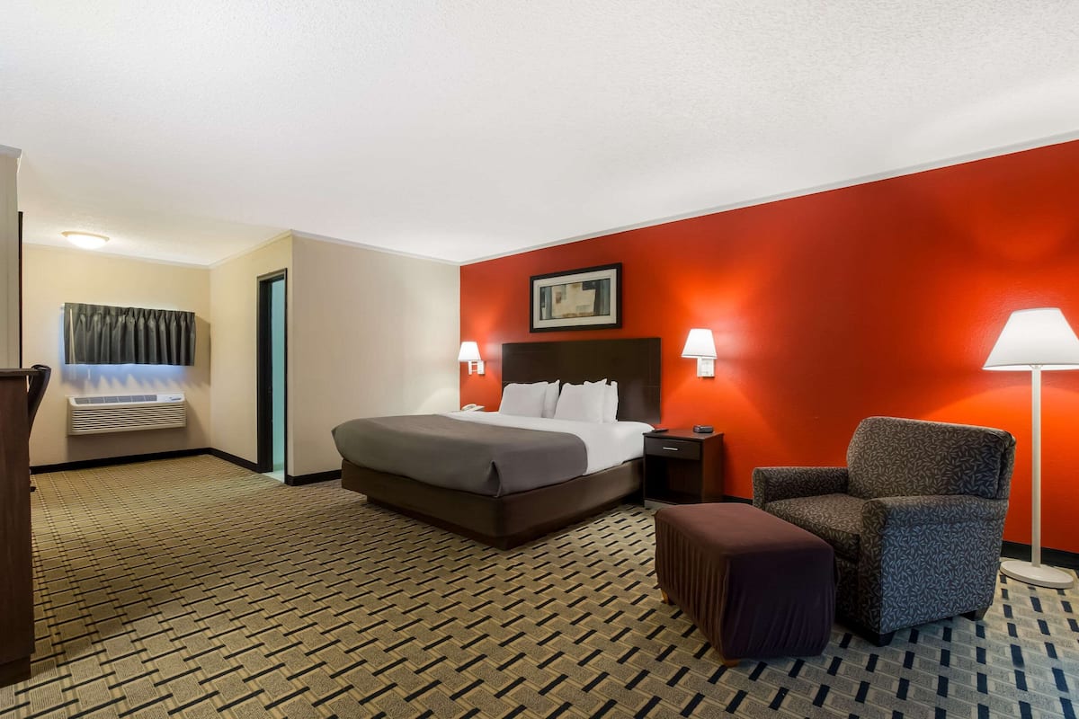 Habitación de hotel con una cama grande, una silla, un escritorio y una lámpara.