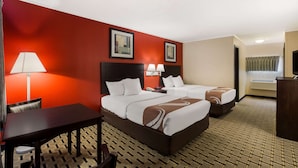 A hotel room with two beds, a desk, and a chair. There are two lamps on the desk and a TV on a stand.