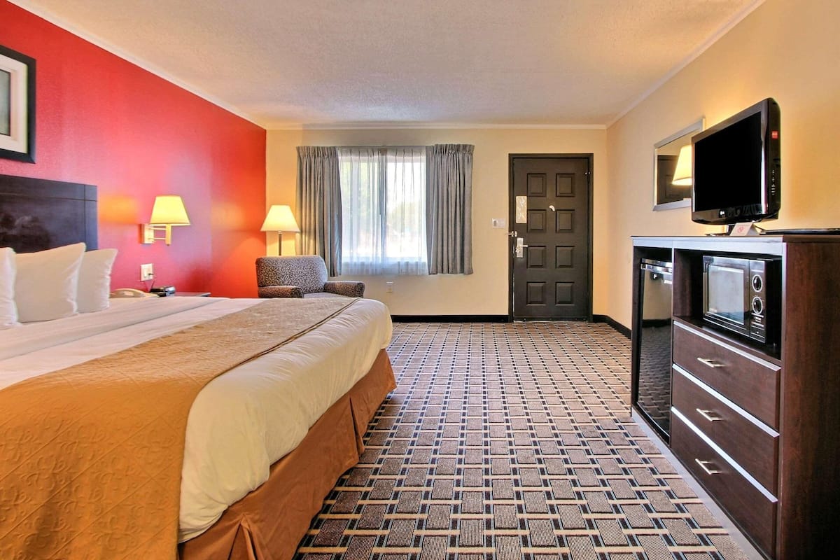 Een hotelkamer met een bed, een bureau, een stoel, een televisie en een magnetron.