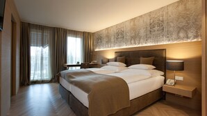Une chambre d’hôtel moderne avec un grand lit, une table de chevet avec une lampe, un bureau et une chaise.
