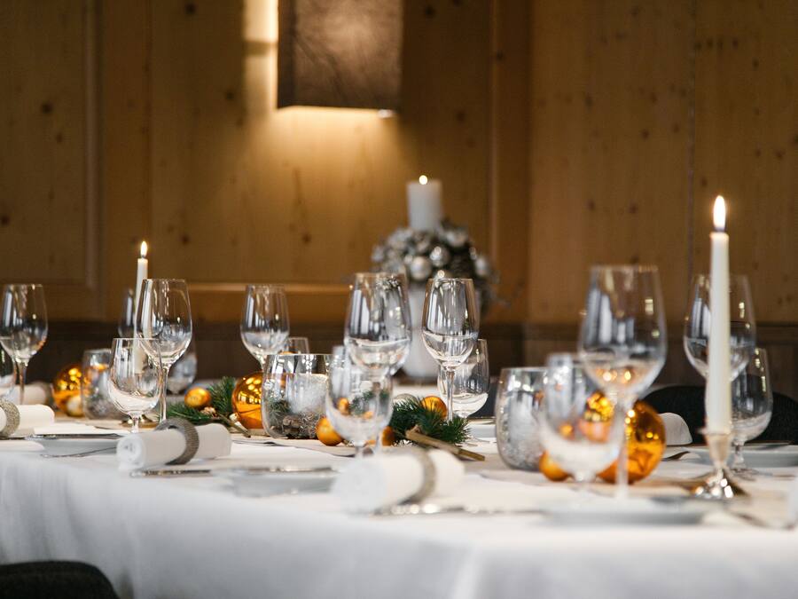 A table set for a formal dinner with multiple wine glasses, plates, and a candle.