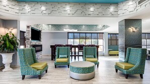 A modern lounge area with patterned chairs, a round ottoman, and a stone fireplace. - Quality Inn & Suites Montgomery East Carmichael Rd (Montgomery)