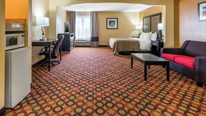 A hotel room with a bed, a desk with a computer, a TV, a microwave, and a coffee maker. - Quality Inn & Suites Montgomery East Carmichael Rd (Montgomery)
