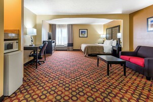 Habitación de hotel con cama, escritorio con computadora, televisor, microondas y cafetera.