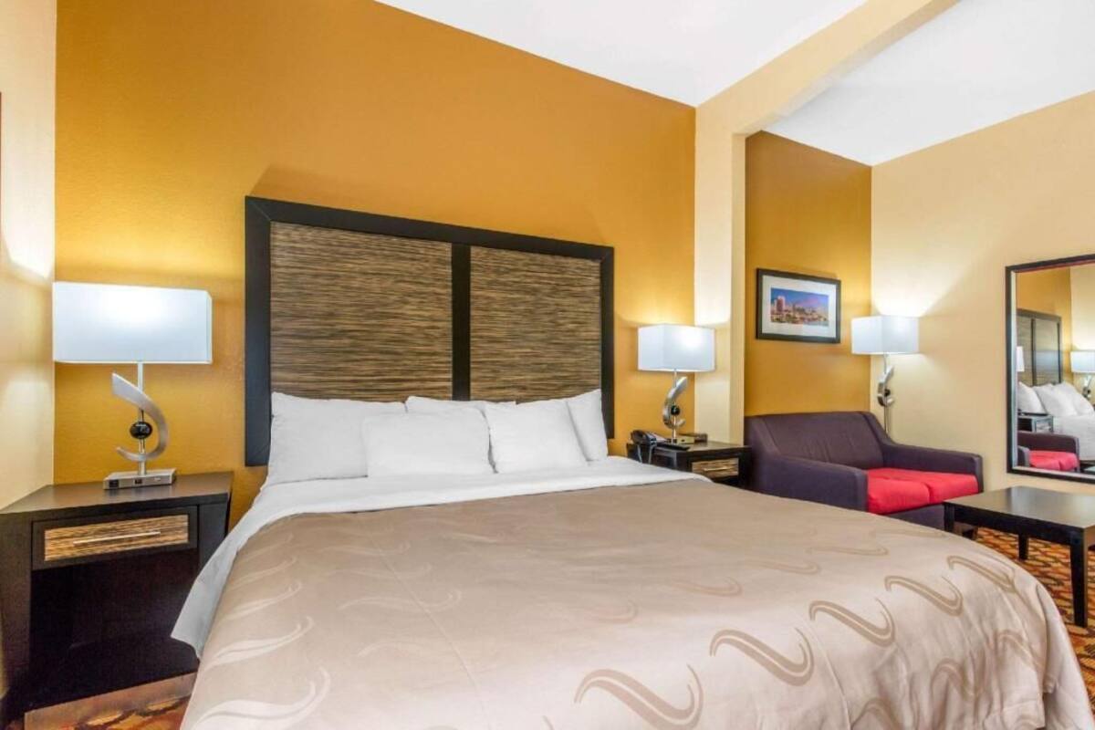 A hotel room with a large bed, two bedside tables, a chair, and a mirror.