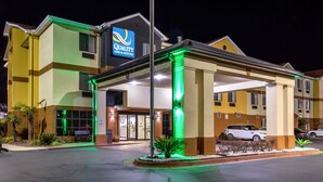 A hotel with a sign reading "Quality Inn & Suites," featuring a covered entrance, a parking lot, and a well-lit facade. - Quality Inn & Suites Montgomery East Carmichael Rd (Montgomery)