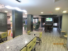 Un restaurante moderno con mesas y sillas altas, una pantalla de televisión y suelo de madera.