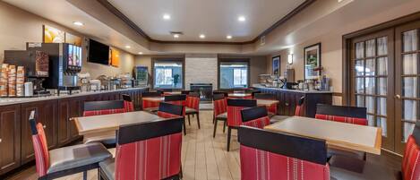 A restaurant with booths and tables, a counter with a coffee machine, and a TV mounted on the wall.