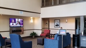Eine Lobby mit Fernseher, der Nachrichten zeigt, einer Uhr und einer Kristallleuchtre.'