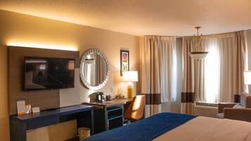 A hotel room with a bed, desk, TV, and a large mirror.