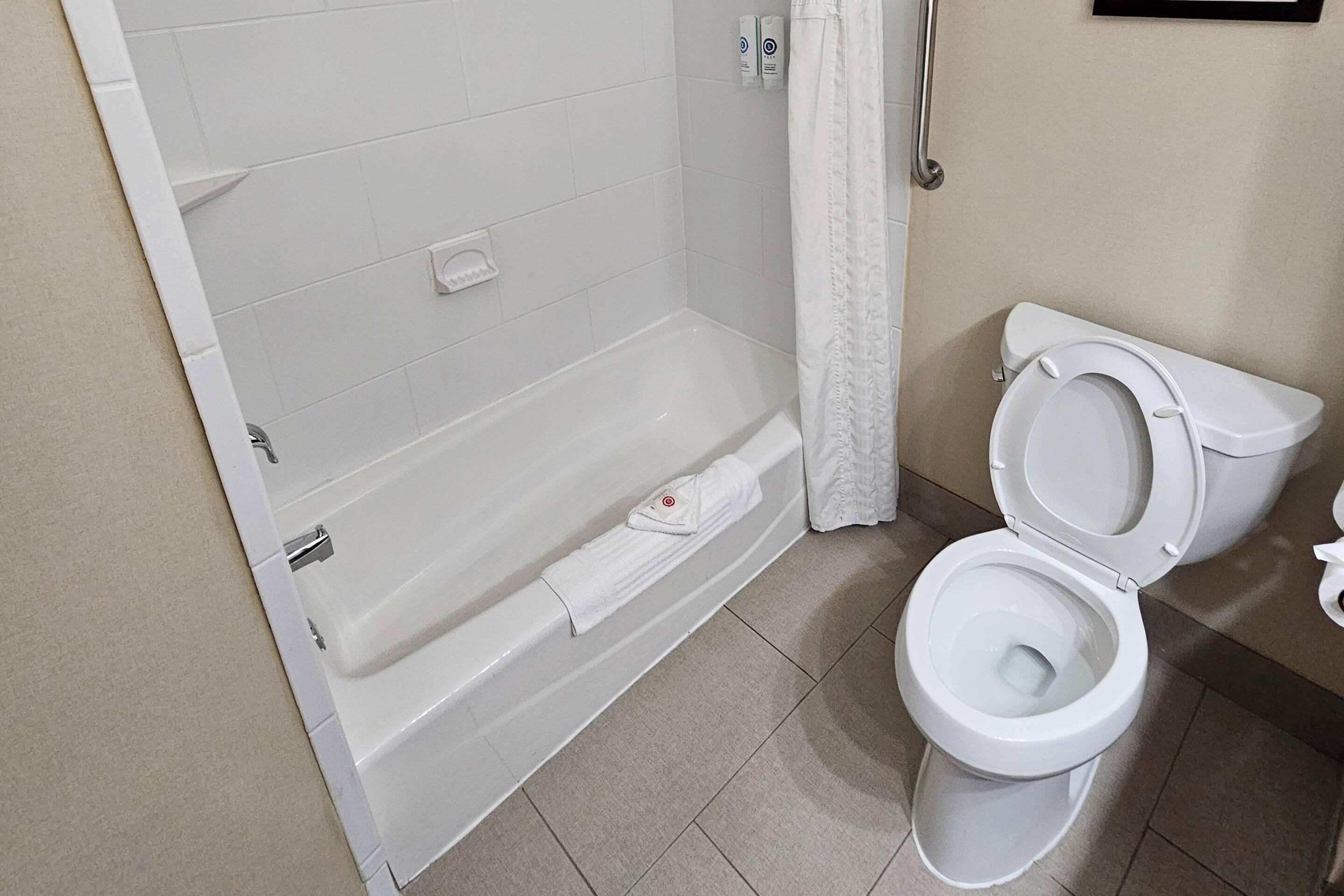 A bathroom with a bathtub, toilet, and a shower curtain.
