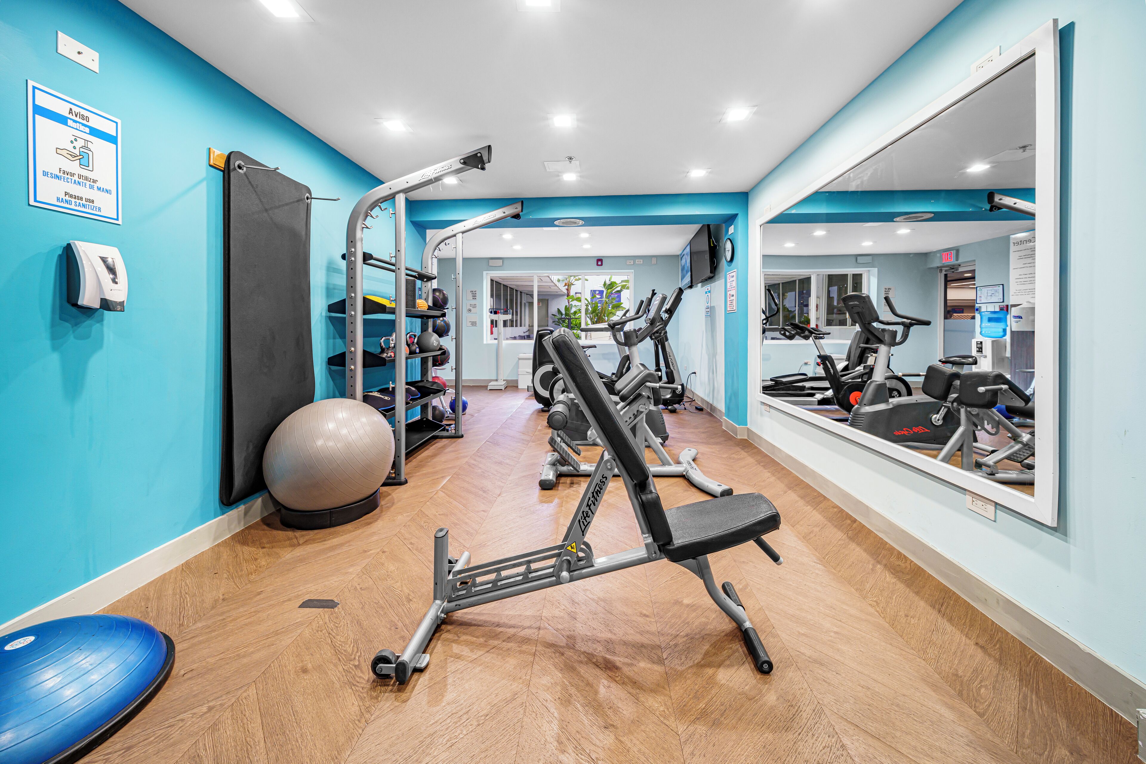 Una palestra con attrezzature per esercizi, uno specchio e una parete blu.