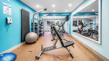 A gym with exercise equipment, a mirror, and a blue wall.