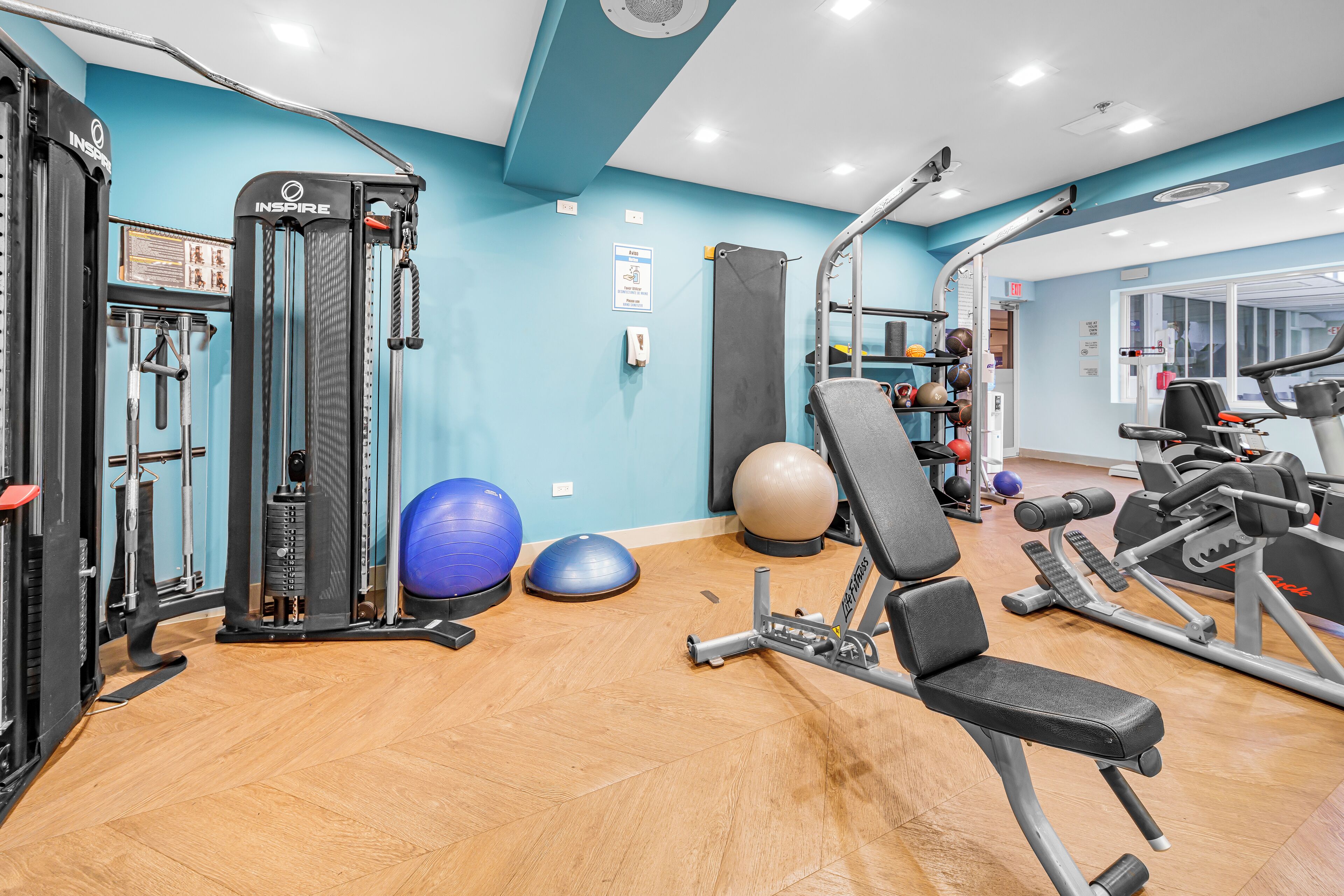 Ein Fitnessraum mit Trainingsgeräten, einer blauen Wand und einem Holzboden.