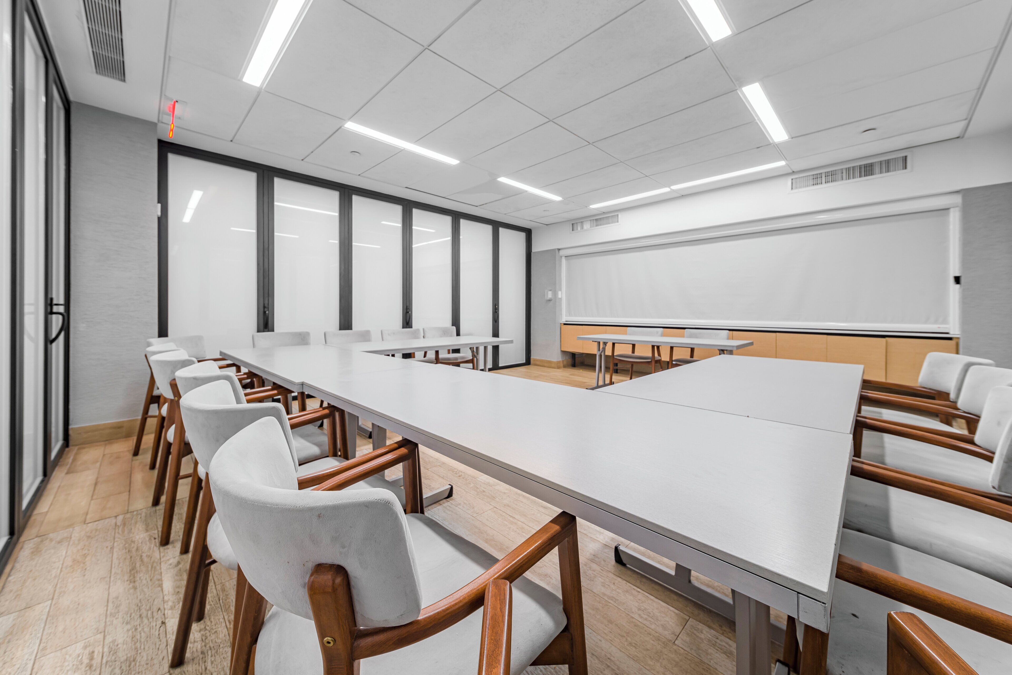 A conference room with a long table, chairs, a projector screen, and a whiteboard.