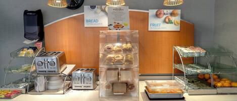 A breakfast buffet with various food items, a clock, and a sign promoting breakfast.