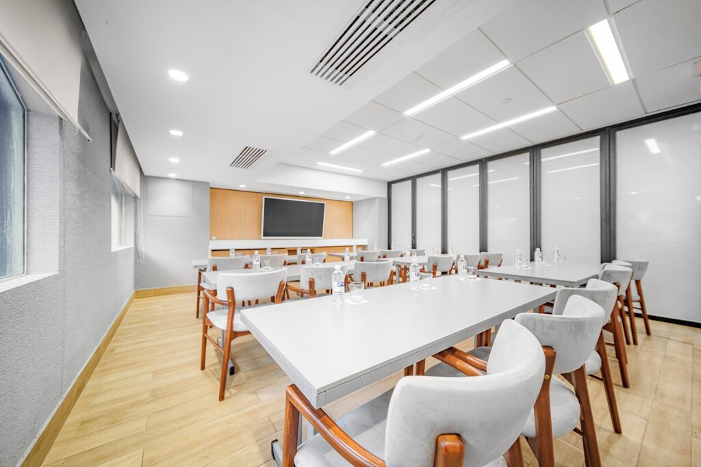 A conference room with a long table, chairs, a whiteboard, and a large window.