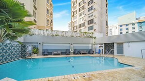 A swimming pool with a tiled edge, surrounded by lounge chairs and a palm tree. - Holiday Inn Express San Juan Condado by IHG (San Juan)