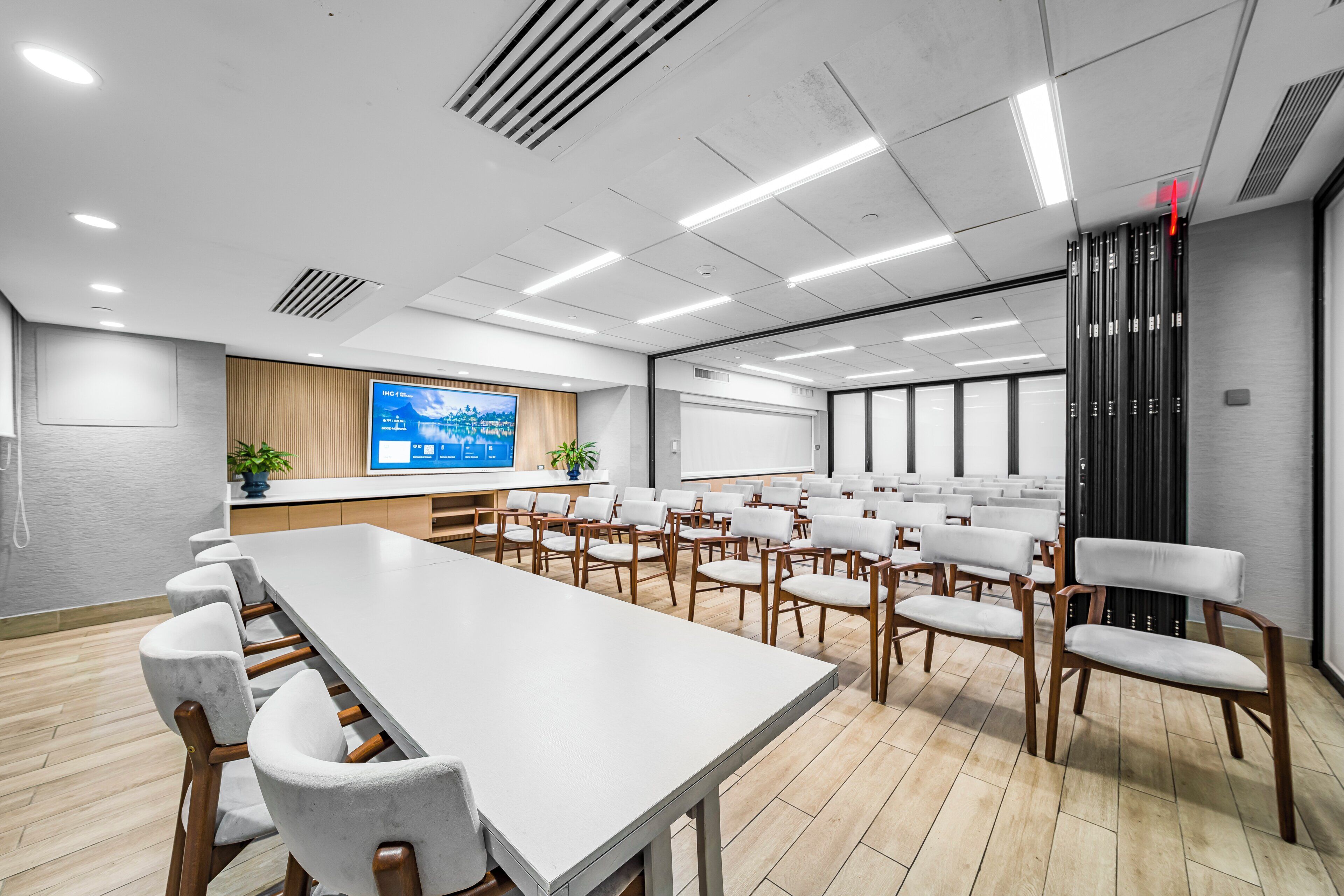 A conference room with a long table, white chairs, a projection screen, and a whiteboard.