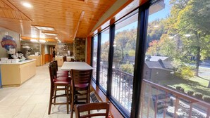 A dining area with a large window overlooking a scenic outdoor view. - Baymont by Wyndham Gatlinburg On The River (Gatlinburg)
