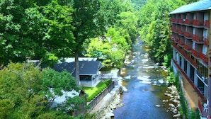 A river running through a lush green area with a building on the right side. - Baymont by Wyndham Gatlinburg On The River (Gatlinburg)