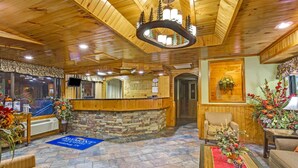 A wooden reception area with a stone counter, a TV, and a sign that reads "Baymont." - Baymont by Wyndham Gatlinburg On The River (Gatlinburg)
