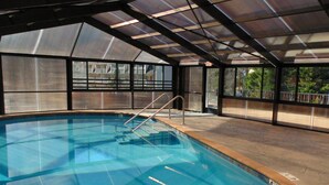 An indoor swimming pool with clear glass walls, metal railings, and a roof structure. - Baymont by Wyndham Gatlinburg On The River (Gatlinburg)
