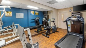 A gym with exercise equipment, a treadmill, and a mirrored wall.