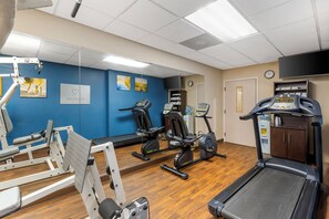 A gym with exercise equipment, a treadmill, and a mirrored wall.