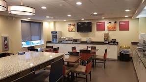 A restaurant with granite countertops, red and black chairs, a flat-screen TV, a coffee machine, and a microwave.